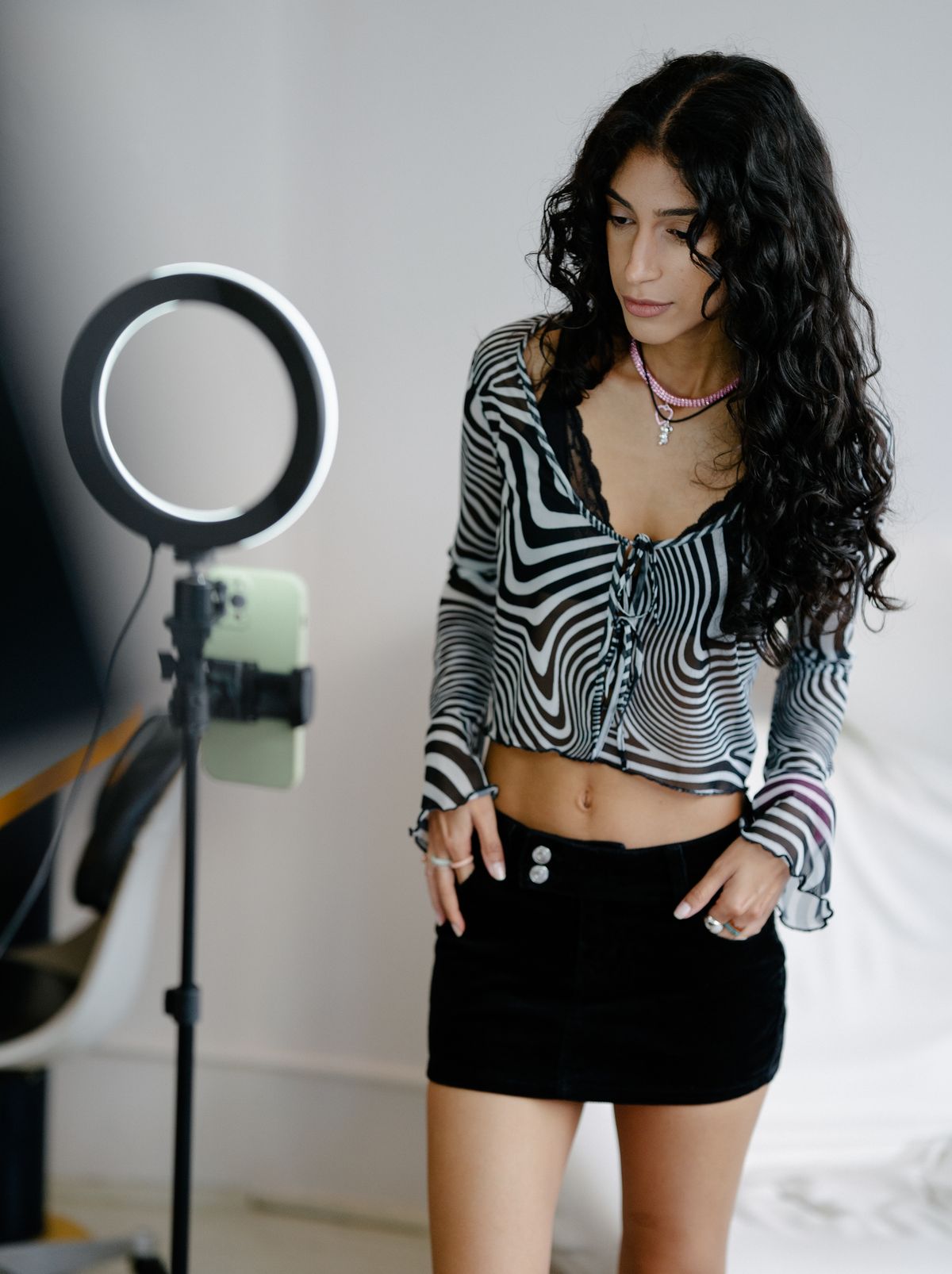 An influencer posing in front of a ring light and phone