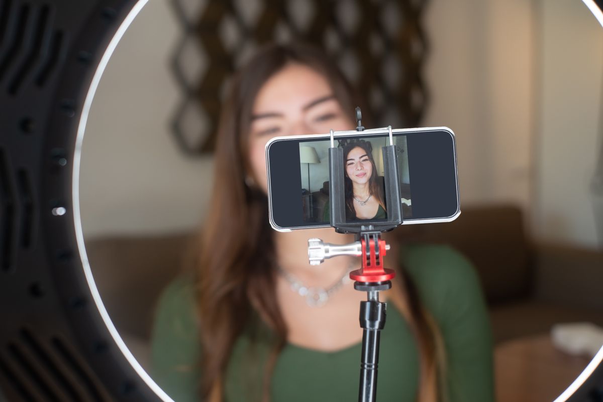 A creator live streaming from home with a phone and ring light