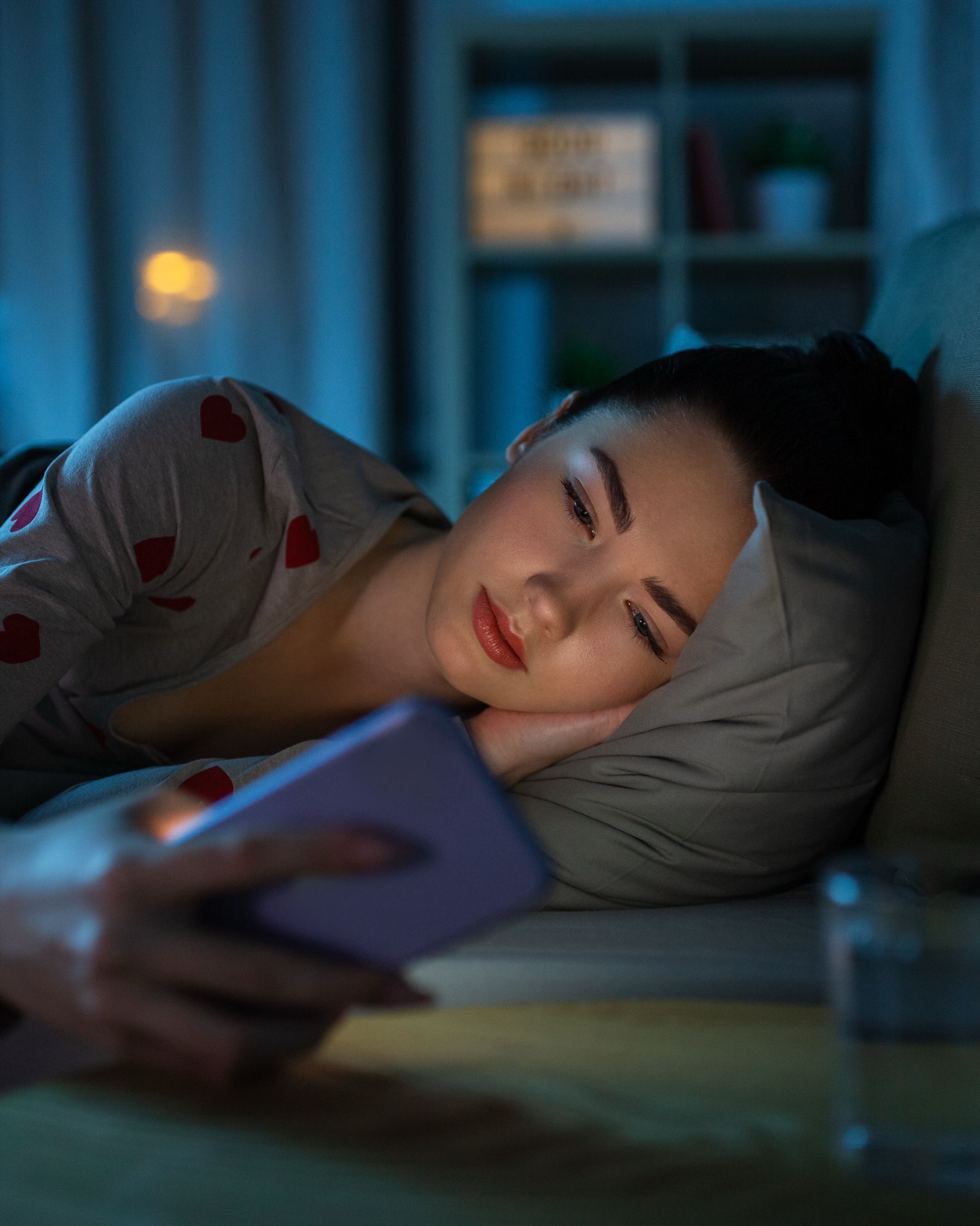 A young woman reading her phone at night under neon light